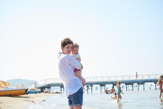 happy mom and baby on beach  have fun while learning to walk and  make first steps