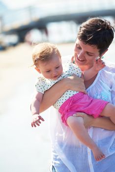 happy mom and baby on beach  have fun while learning to walk and  make first steps