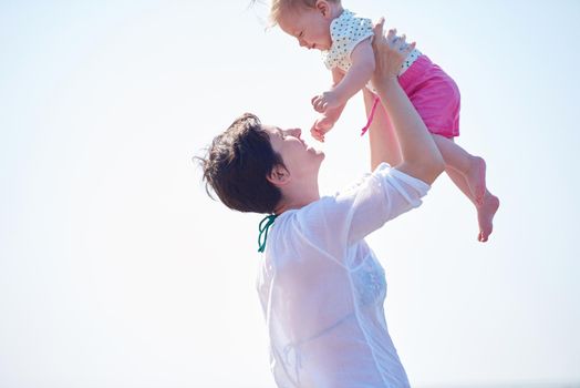 happy mom and baby on beach  have fun while learning to walk and  make first steps