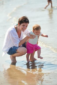 happy mom and baby on beach  have fun while learning to walk and  make first steps