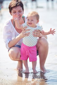 happy mom and baby on beach  have fun while learning to walk and  make first steps