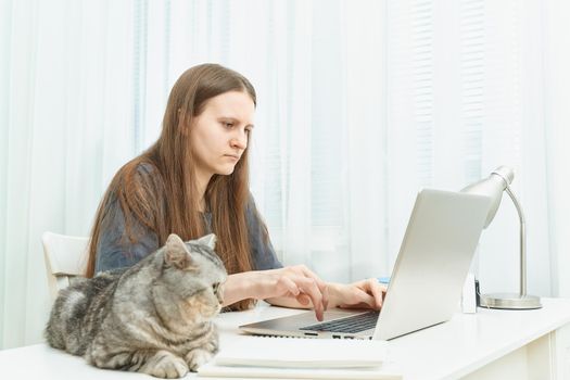 Distance education for students. Quarantine, self-isolation, sociophobia. Young girl listens to online learning, teleworking, online lectures.Woman look at laptop. Freelancer, Digital Nomad Concept