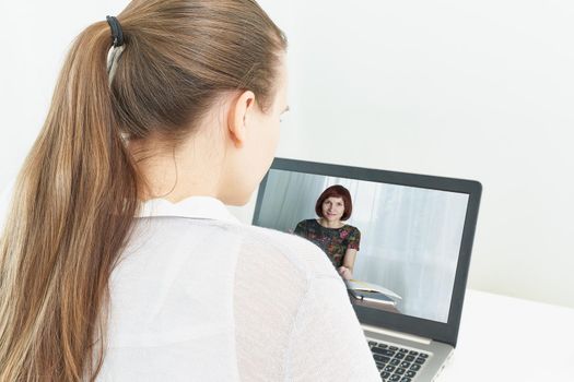 Distance learning for students. Quarantine, self-isolation, social phobia. Young girl listens to online training, telework, rear view. Woman looks at laptop. Freelancer, Concept Of Digital Nomad