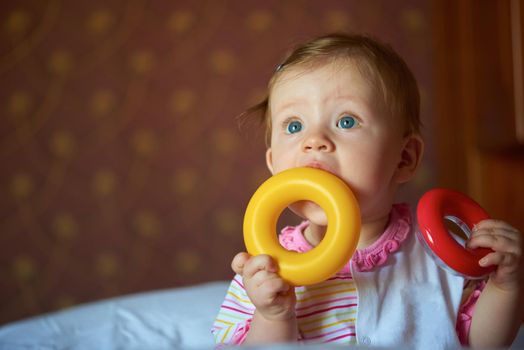 happy baby with first teeth smilling and play with toys