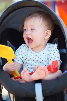 cutte little baby have fun and play with toys in carriage on summer vacation on beach