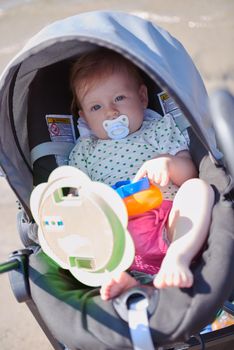 cutte little baby have fun and play with toys in carriage on summer vacation on beach