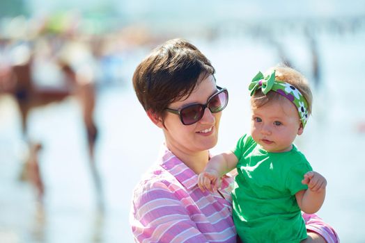 happy mom and baby on beach  have fun while learning to walk and  make first steps