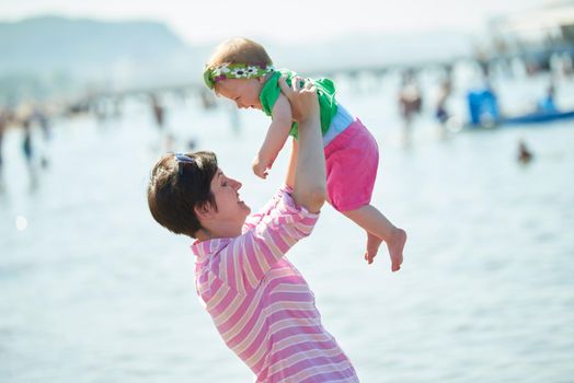 happy mom and baby on beach  have fun while learning to walk and  make first steps