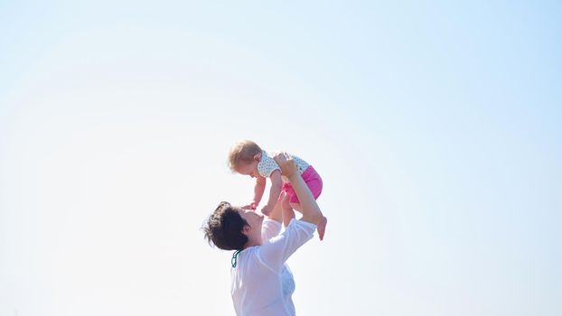 happy mom and baby on beach  have fun while learning to walk and  make first steps