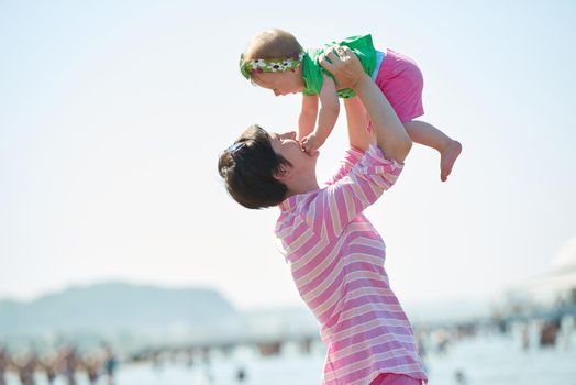 happy mom and baby on beach  have fun while learning to walk and  make first steps