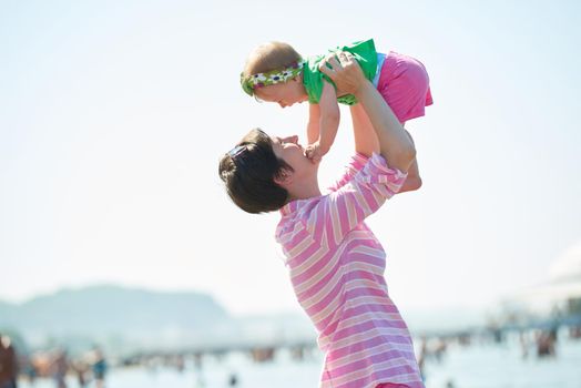 happy mom and baby on beach  have fun while learning to walk and  make first steps