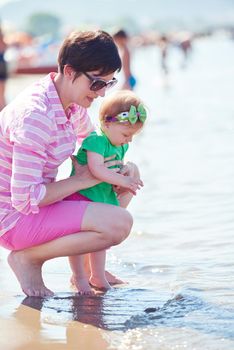 happy mom and baby on beach  have fun while learning to walk and  make first steps