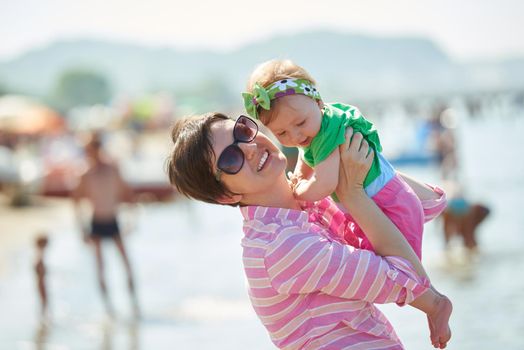 happy mom and baby on beach  have fun while learning to walk and  make first steps