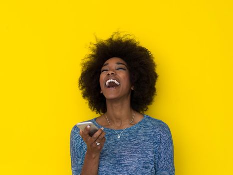 Young Happy African American Woman Using mobile phone  Isolated on a yellow background