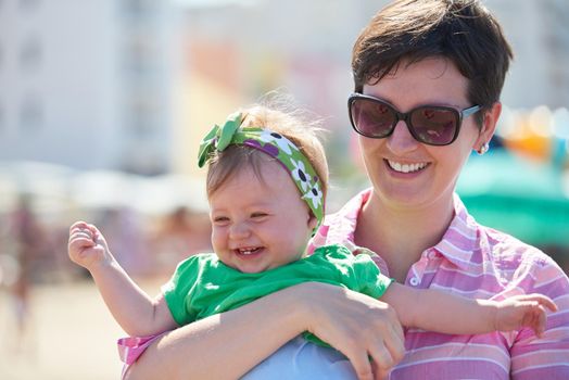 happy mom and baby on beach  have fun while learning to walk and  make first steps