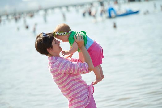 happy mom and baby on beach  have fun while learning to walk and  make first steps