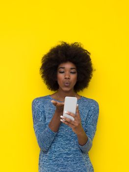 Young Happy African American Woman Using mobile phone  Isolated on a yellow background