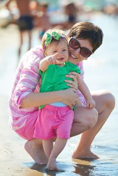 happy mom and baby on beach  have fun while learning to walk and  make first steps