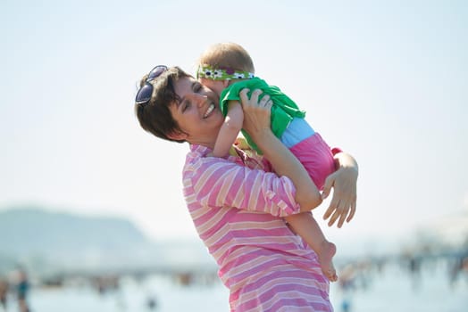 happy mom and baby on beach  have fun while learning to walk and  make first steps