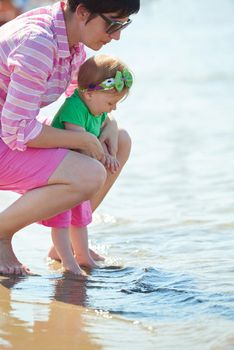 happy mom and baby on beach  have fun while learning to walk and  make first steps