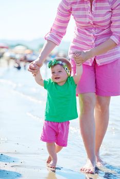 happy mom and baby on beach  have fun while learning to walk and  make first steps