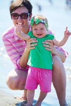 happy mom and baby on beach  have fun while learning to walk and  make first steps