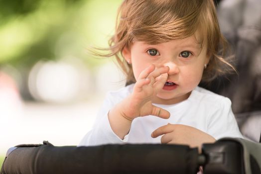 little and very beautiful baby girl sitting in the pram and waiting for mom