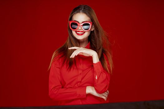 attractive woman in red shirt sunglasses fashion red background. High quality photo