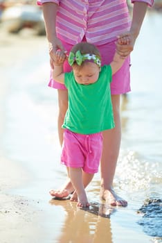 happy mom and baby on beach  have fun while learning to walk and  make first steps