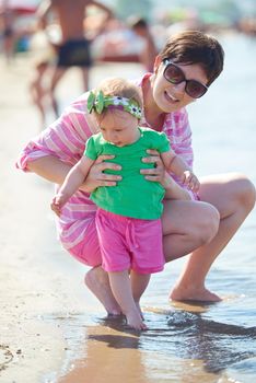 happy mom and baby on beach  have fun while learning to walk and  make first steps