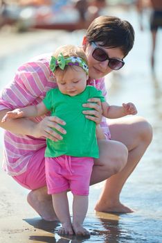 happy mom and baby on beach  have fun while learning to walk and  make first steps