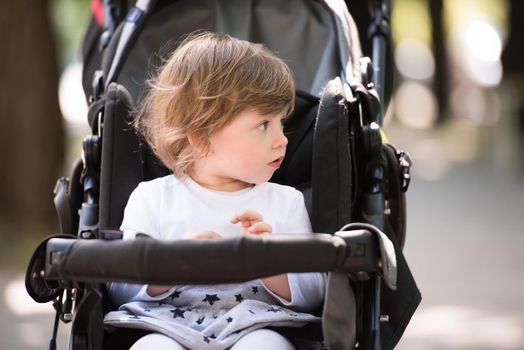 little and very beautiful baby girl sitting in the pram and waiting for mom