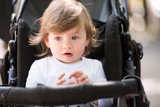 little and very beautiful baby girl sitting in the pram and waiting for mom