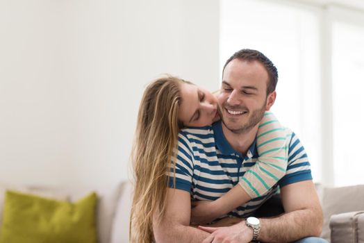 young handsome couple enjoys hugging on the sofa in their luxury home villa