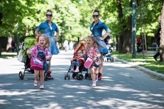 Young beautiful twins mother with children enjoying a sunny day in city park