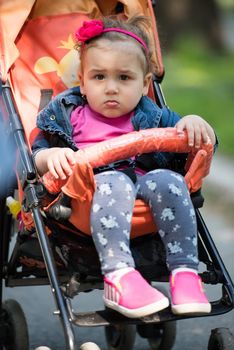 little and very beautiful baby girl sitting in the pram and waiting for mom