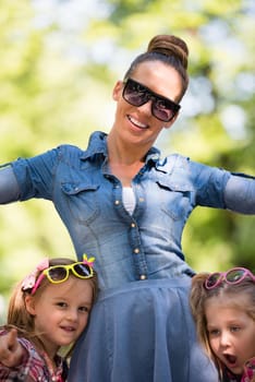 young beautiful mother enjoying with her daughters on a sunny day in the park