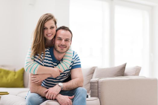 young handsome couple enjoys hugging on the sofa in their luxury home villa