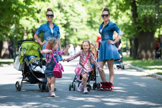 Young beautiful twins mother with children enjoying a sunny day in city park