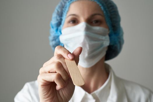 Female doctor in medical mask and uniform check up condition of throat. Illness and Covid-19 protection, medical safety. Close up