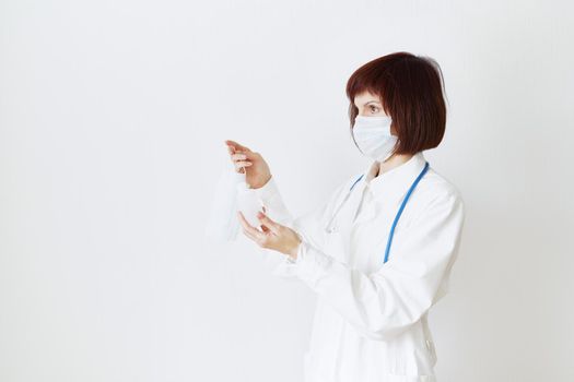 Female doctor in medical mask and uniform offers mask and disinfectant in bottle to prevent from coronavirus. Covid-19 protection, medical information. Copy space