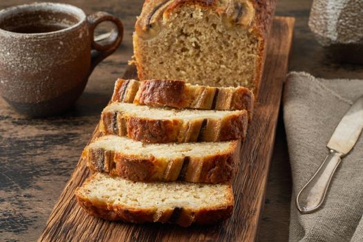 Banana bread. Cake with banana, traditional american cuisine. Slices of loaf. Dark background, black table.