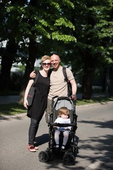 love, parenthood, family, season and people concept  Portrait of a young smiling couple with baby pram in summer park