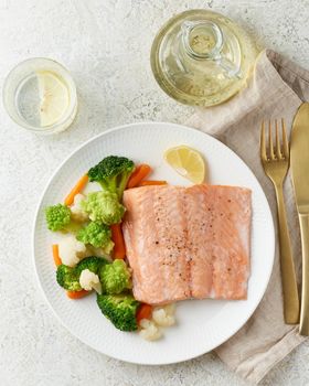 Steam salmon and vegetables, Paleo, keto, fodmap, dash diet. Mediterranean diet with steamed fish. Healthy concept, white plate on gray table, gluten free, lectine free, vertical