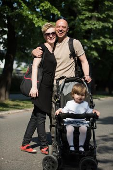 love, parenthood, family, season and people concept  Portrait of a young smiling couple with baby pram in summer park