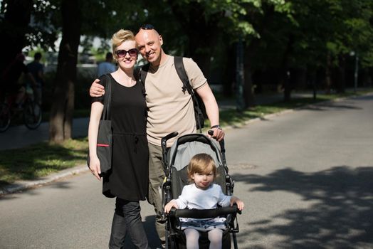 love, parenthood, family, season and people concept  Portrait of a young smiling couple with baby pram in summer park