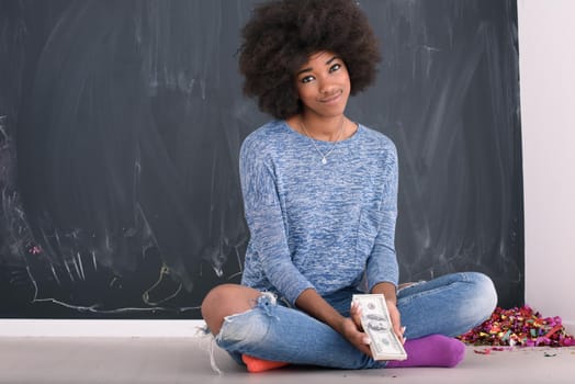 Portrait of a beautiful smiling afro american woman holding money isolated on a gray background