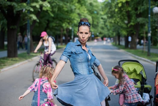 young beautiful mother enjoying with her daughters on a sunny day in the park