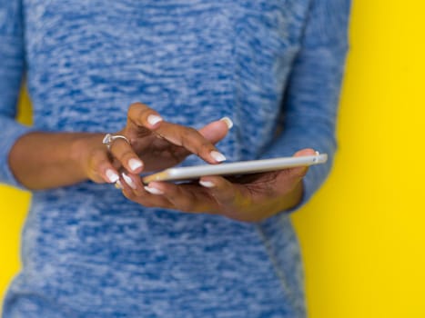 Young Happy African American Woman Using Digital Tablet  Isolated on a yellow background