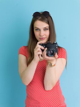 portrait of a smiling pretty girl taking photo on a retro camera isolated over blue background